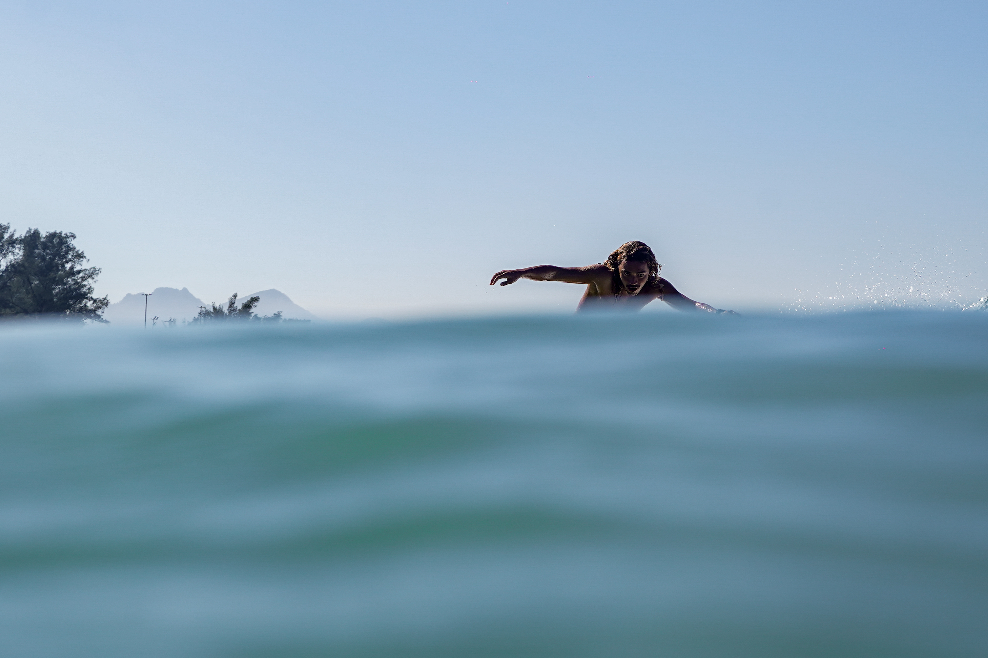 Vista aérea de surfistas remando em direção às ondas na Praia da Macumba, um dos melhores picos de surf da Zona Oeste do Rio de Janeiro