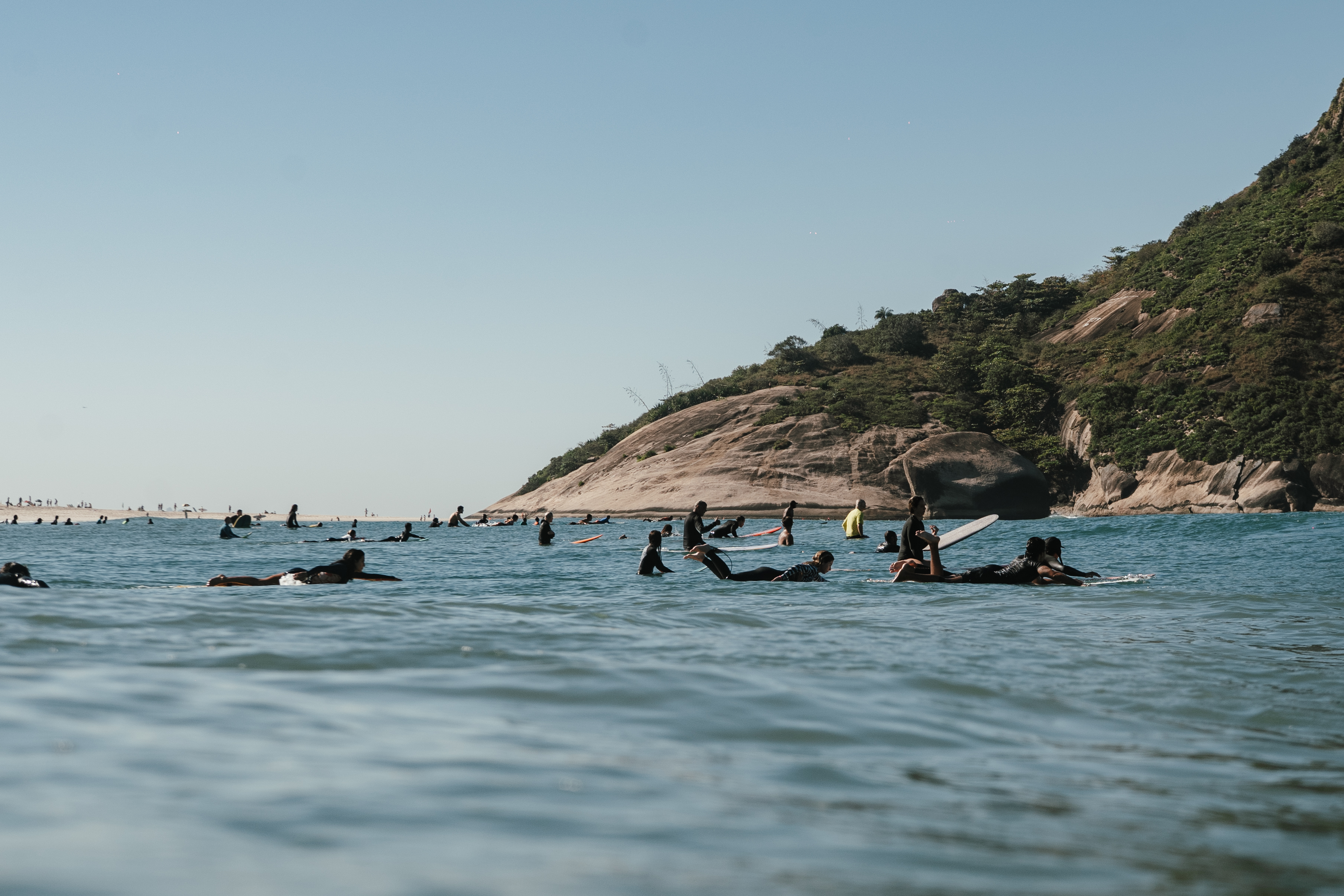 Família com diferentes gerações caminhando com pranchas de surf na areia da Praia da Macumba, Rio de Janeiro